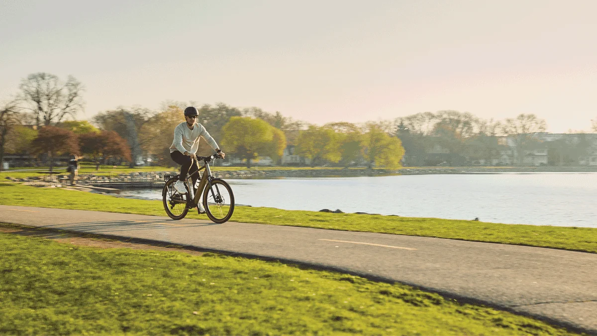 Rider cruising an e-bike along a lakeside path at golden hour