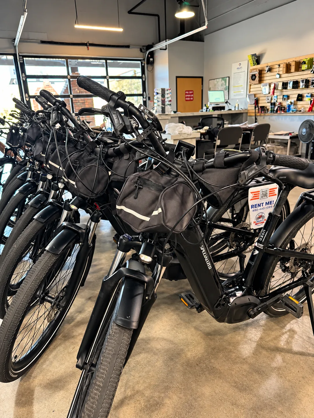 PedalJets rental e-bikes lined up and prepped with handlebar bags, lights and RENT ME tags