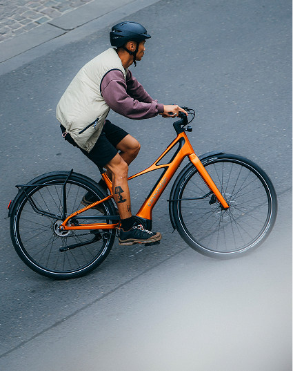 Rider commuting on an orange Cannondale electric city bike